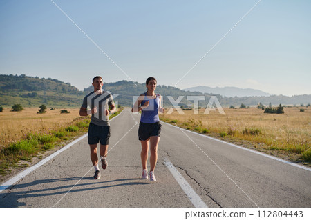 Energized by the beauty of nature, a couple powers through their morning run, their bodies and spirits invigorated. Energized by the beauty of nature, a couple powers through their morning run, their bodies and spirits invigorated. 112804443