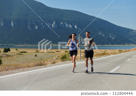 Energized by the beauty of nature, a couple powers through their morning run, their bodies and spirits invigorated. 112804444