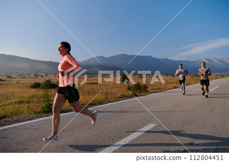 A group of friends maintains a healthy lifestyle by running outdoors on a sunny day, bonding over fitness and enjoying the energizing effects of exercise and nature 112804451