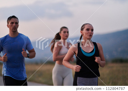 A diverse group of runners trains together at sunset. A diverse group of runners trains together at sunset. 112804787