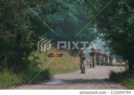 Elite military unit parading and securing the forest, utilizing drones for terrain scanning and reconnaissance, showcasing their advanced skills and specialized training in high risk operations 112804794