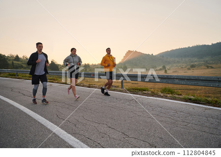 Running towards a common goal, a group of colleagues braves the misty morning air, their determination evident in every stride. Running towards a common goal, a group of colleagues braves the misty morning air, their determination evident in every stride. 112804845