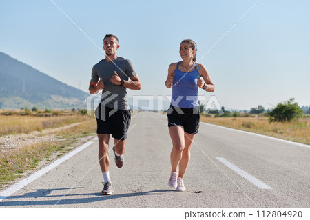 Energized by the beauty of nature, a couple powers through their morning run, their bodies and spirits invigorated. Energized by the beauty of nature, a couple powers through their morning run, their bodies and spirits invigorated. 112804920