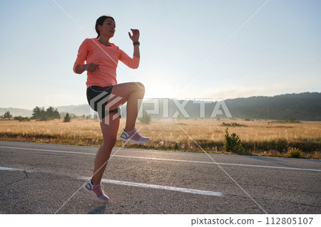 Determined Stretch: Athletic Woman Embraces Post-Run Flexibility in Nature. Determined Stretch: Athletic Woman Embraces Post-Run Flexibility in Nature. 112805107