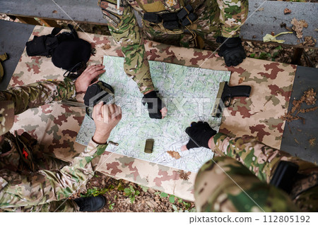 A highly trained military unit strategizes and organizes a tactical mission while studying a military map during a briefing session 112805192