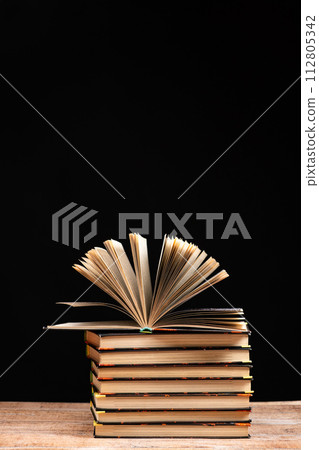 Stack of books on black background, open book, space for text. Stack of books on black background, open book, space for text. 112805342