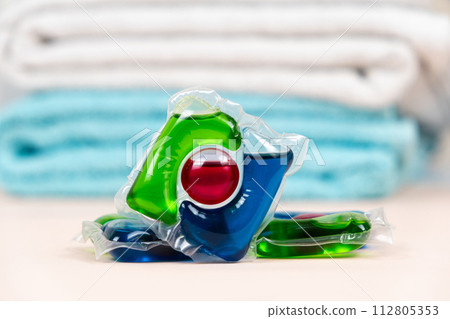 Laundry pods capsules on beige background with soft towels 112805353