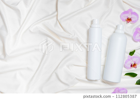 Liquid laundry detergent and fabric softener on bedding, orchid flowers, space for text Liquid laundry detergent and fabric softener on bedding, orchid flowers, space for text 112805387