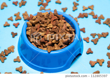 Dry cat food in a plate on a blue background, close-up. Complete Cat Nutrition 112805397