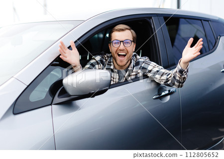Man customer sitting in car salon and smiling, choosing auto and wanting to buy new automobile in showroom dealership store. Car sales concept. Man customer sitting in car salon and smiling, choosing auto and wanting to buy new automobile in showroom dealership store. Car sales concept. 112805652