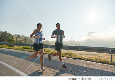 Energized by the beauty of nature, a couple powers through their morning run, their bodies and spirits invigorated. Energized by the beauty of nature, a couple powers through their morning run, their bodies and spirits invigorated. 112805747
