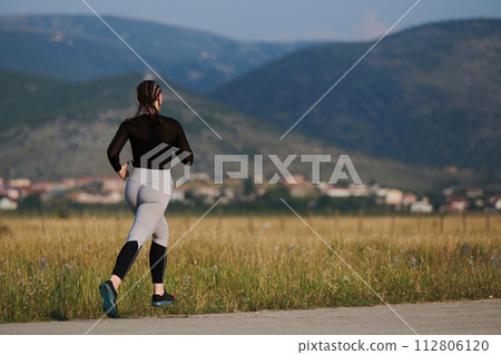 A determined woman athlete trains for success in the morning sun. A determined woman athlete trains for success in the morning sun. 112806120