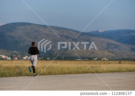 A determined woman athlete trains for success in the morning sun. A determined woman athlete trains for success in the morning sun. 112806137