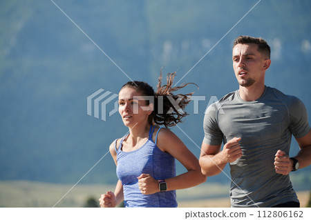Energized by the beauty of nature, a couple powers through their morning run, their bodies and spirits invigorated. Energized by the beauty of nature, a couple powers through their morning run, their bodies and spirits invigorated. 112806162
