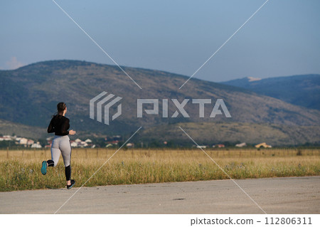 A determined woman athlete trains for success in the morning sun. A determined woman athlete trains for success in the morning sun. 112806311