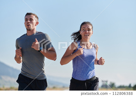 Energized by the beauty of nature, a couple powers through their morning run, their bodies and spirits invigorated. Energized by the beauty of nature, a couple powers through their morning run, their bodies and spirits invigorated. 112806388