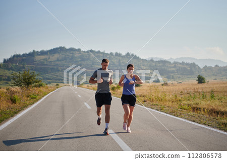 Energized by the beauty of nature, a couple powers through their morning run, their bodies and spirits invigorated. Energized by the beauty of nature, a couple powers through their morning run, their bodies and spirits invigorated. 112806578