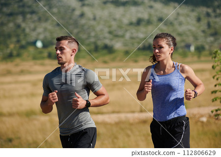 Energized by the beauty of nature, a couple powers through their morning run, their bodies and spirits invigorated. Energized by the beauty of nature, a couple powers through their morning run, their bodies and spirits invigorated. 112806629