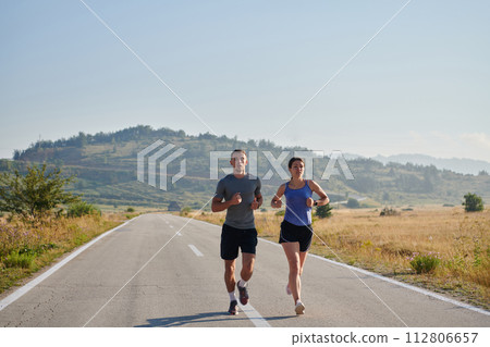 Energized by the beauty of nature, a couple powers through their morning run, their bodies and spirits invigorated. 112806657