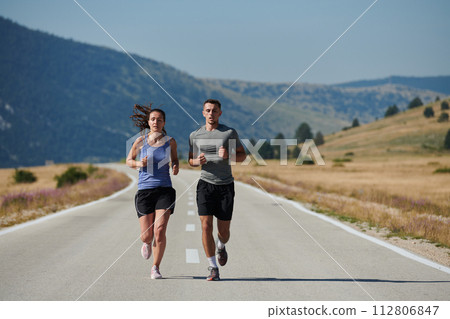 Energized by the beauty of nature, a couple powers through their morning run, their bodies and spirits invigorated. 112806847