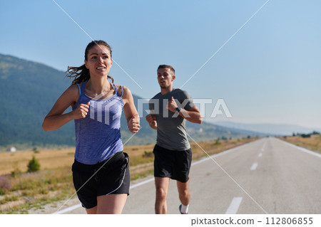 Energized by the beauty of nature, a couple powers through their morning run, their bodies and spirits invigorated. 112806855