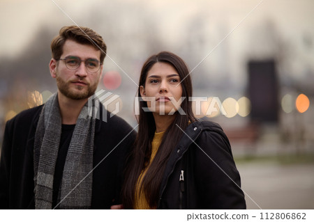 A romantic couple embraces in a tender hug as they stroll through the city streets, enjoying leisure time together in each other's company 112806862