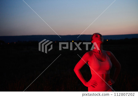 Athlete Strikes a Pose in Red-Lit Nighttime Glow 112807202