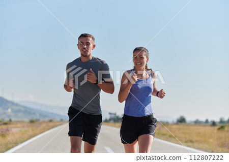 Energized by the beauty of nature, a couple powers through their morning run, their bodies and spirits invigorated. Energized by the beauty of nature, a couple powers through their morning run, their bodies and spirits invigorated. 112807222