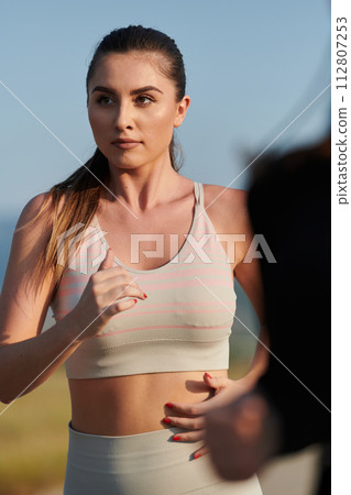 A determined woman athlete trains for success in the morning sun. A determined woman athlete trains for success in the morning sun. 112807253