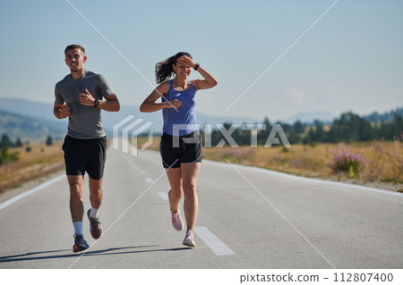 Energized by the beauty of nature, a couple powers through their morning run, their bodies and spirits invigorated. Energized by the beauty of nature, a couple powers through their morning run, their bodies and spirits invigorated. 112807400