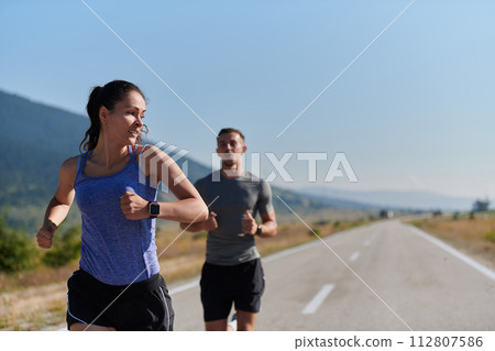 Energized by the beauty of nature, a couple powers through their morning run, their bodies and spirits invigorated. 112807586