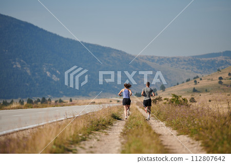 Energized by the beauty of nature, a couple powers through their morning run, their bodies and spirits invigorated. Energized by the beauty of nature, a couple powers through their morning run, their bodies and spirits invigorated. 112807642