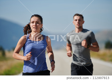 Energized by the beauty of nature, a couple powers through their morning run, their bodies and spirits invigorated. 112807813