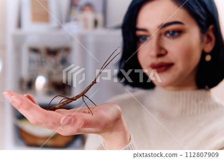 Young Woman Captured in a Beautiful Moment with Her Stick Insect (Medauroidea Extradentata) Young Woman Captured in a Beautiful Moment with Her Stick Insect (Medauroidea Extradentata) 112807909