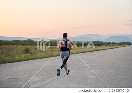 Solo Stride: Determined Athlete Woman Embarks on Fitness Journey for Marathon Preparation. Solo Stride: Determined Athlete Woman Embarks on Fitness Journey for Marathon Preparation. 112807940
