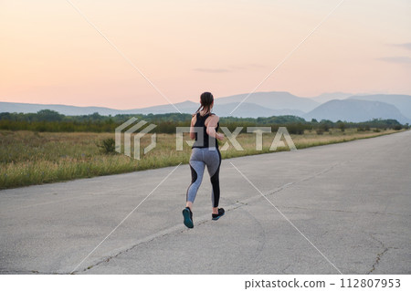 Solo Stride: Determined Athlete Woman Embarks on Fitness Journey for Marathon Preparation. 112807953