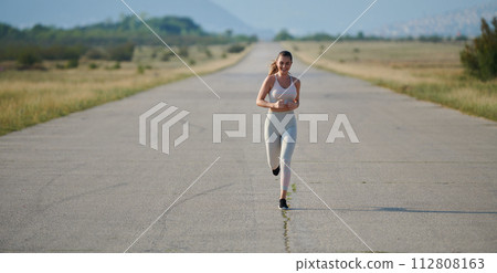 A determined woman athlete trains for success in the morning sun. A determined woman athlete trains for success in the morning sun. 112808163