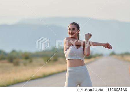 Determined Stretch: Athletic Woman Embraces Post-Run Flexibility in Nature. Determined Stretch: Athletic Woman Embraces Post-Run Flexibility in Nature. 112808188