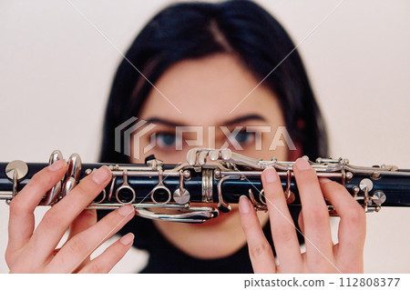 Graceful Brunette Musician Posing with Clarinet on White Background Graceful Brunette Musician Posing with Clarinet on White Background 112808377