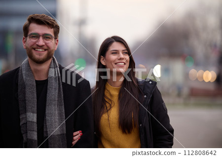 A romantic couple embraces in a tender hug as they stroll through the city streets, enjoying leisure time together in each other's company 112808642