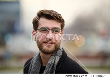 A handsome young man, dressed in a stylish suit, tie, and glasses, exudes the appearance of a serious and confident businessman 112808659