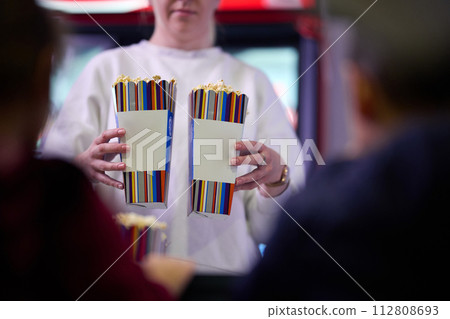 A vendor stands outside the cinema, holding freshly popped popcorn to sell to moviegoers before they enter the theater 112808693