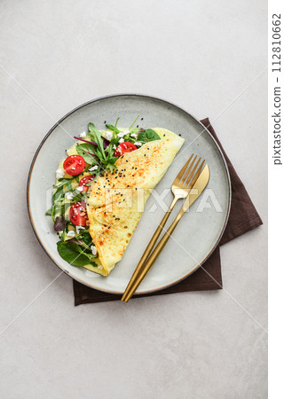 Omelette with herbs, feta cheese and cherry tomatoes 112810662