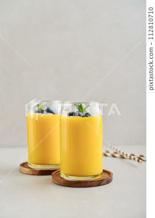 Refreshing and healthy mango smoothie with coconut flakes and fresh blueberries Refreshing and healthy mango smoothie with coconut flakes and fresh blueberries 112810710