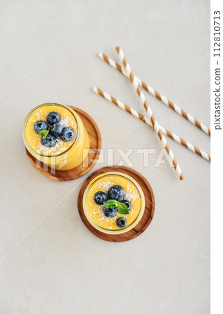 Refreshing and healthy mango smoothie with coconut flakes and fresh blueberries Refreshing and healthy mango smoothie with coconut flakes and fresh blueberries 112810713
