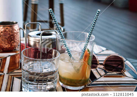 Cold drinks on mosaic table in cafe. Gin tonic cocktail, spritz aperol in drinking glass on restaurant terrace. Fresh summer drinks, water with fruits Cold drinks on mosaic table in cafe. Gin tonic cocktail, spritz aperol in drinking glass on restaurant terrace. Fresh summer drinks, water with fruits 112811045