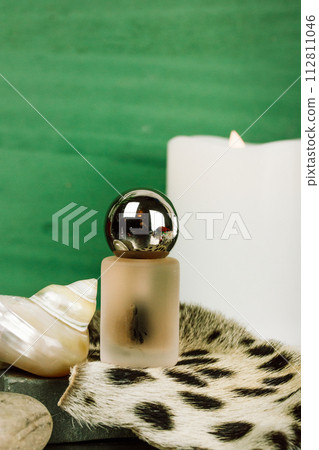 Beautiful bottle with essential oil for face skin care. Natural leopard skin, pearl shell, candle. Vintage glamour composition, nostalgic still life. 112811046