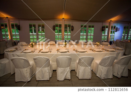 Elegant Banquet Setup with Pristine White Linens and Intimate Lighting Elegant Banquet Setup with Pristine White Linens and Intimate Lighting 112811656