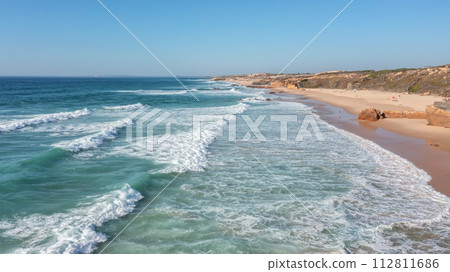 An aerial view of Malhao beach popular for surfing and vacationing tourists. low above the waves An aerial view of Malhao beach popular for surfing and vacationing tourists. low above the waves 112811686