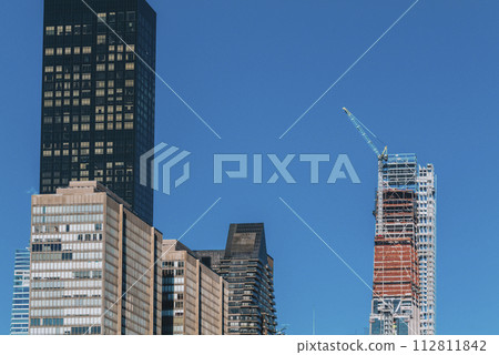 Building under construction with Crane on a Building in New York City on a blue sky background 112811842